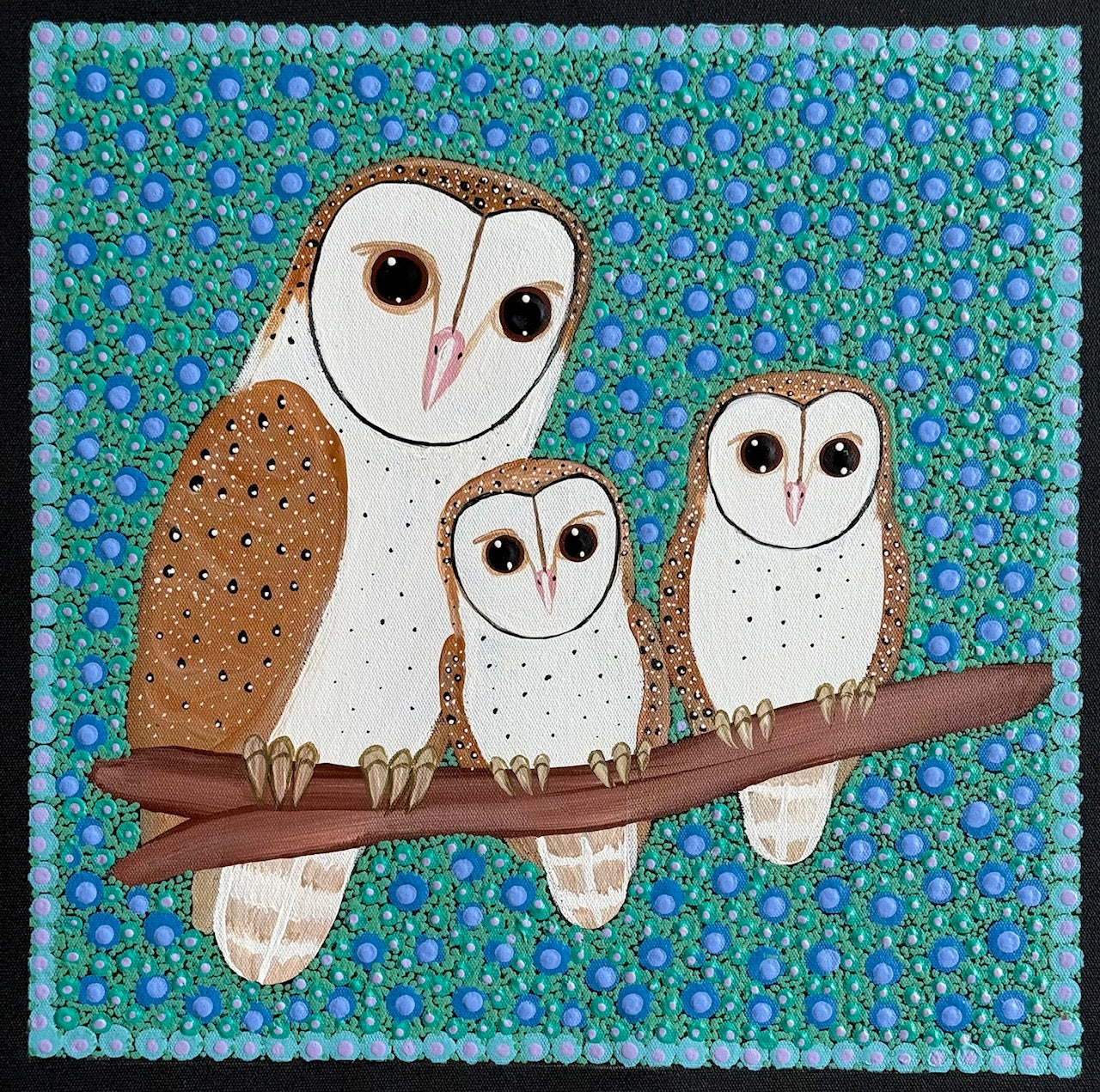 A small piece of Aboriginal Art by Kathleen Buzzacott depicting three Barn Owls sitting on a branch. The background is a highly detailed combination of green and blue dots