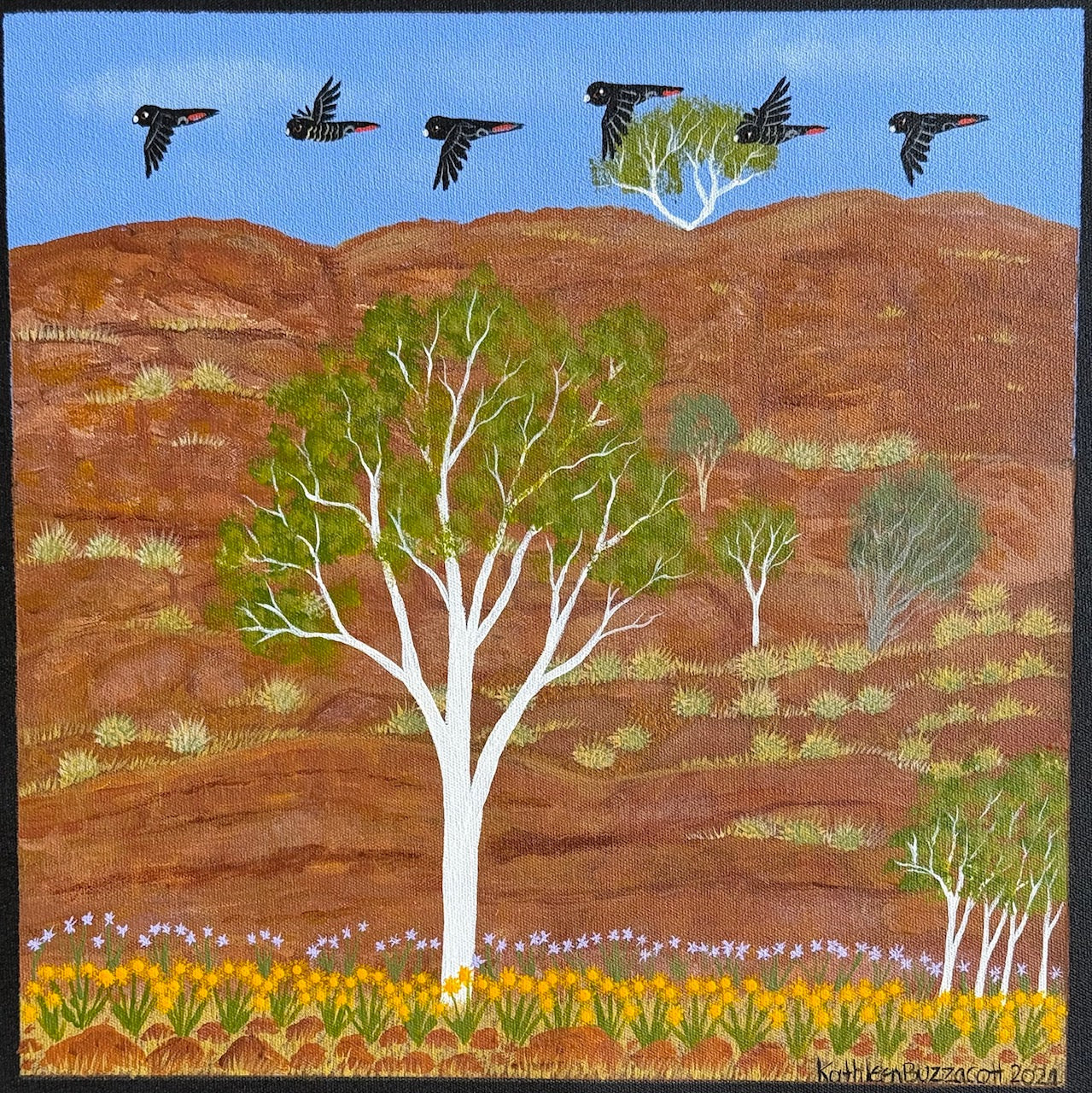 A small landscape painting by Aboriginal Artist Kathleen Buzzacott, depicting West MacDonnell Ranges. Red-tailed black cockatoos fly over a mountain ranged, with white gum trees and colourful flowers sprouting from the earth.